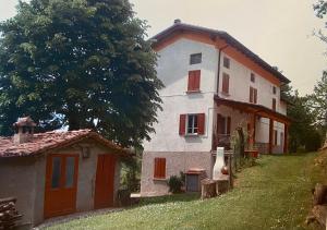 duży biały dom z czerwonymi okiennicami i drzewem w obiekcie Casa di campagna w mieście Marola
