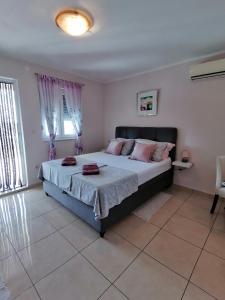 a bedroom with a large bed with pink pillows at Apartmani Marijana in Lozovac