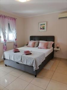 Apartmani Marijana في لازوفاك: غرفة نوم مع سرير مع وسائد وردية عليه