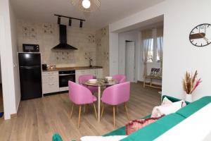 uma cozinha e sala de estar com cadeiras cor-de-rosa e uma mesa em Apartamentos La Escapada em Alhama de Aragón