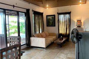 een woonkamer met een bank en een ventilator bij Tropical House Beach Bungalow in Kesembu