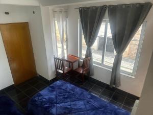 um quarto com uma cama, uma mesa e duas janelas em Virginia hotel em La Quiaca