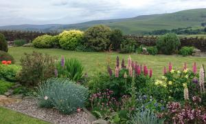 a garden with colorful flowers and a fence at Parkin House Guest House in Todmorden