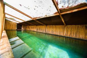 une piscine d'eau bleue et un plafond en bois dans l'établissement Dar Tawarta Guest House Dakhla, à Dakhla