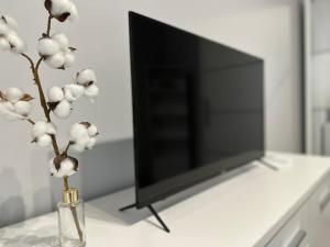 a vase with white flowers in front of a television at Premium Apartment - Evergreen - SELF CHECK-IN - Parking in Rzeszów