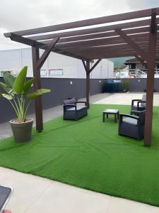 un patio con césped verde y pérgola de madera en Flat Home Business 202 Centro Pomerode en Pomerode