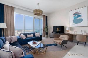 a living room with a blue couch and a tv at Everluxe Palm Views 3 Bedroom in Dubai