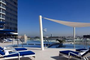 a patio with chairs and a pool with a umbrella at Everluxe Palm Views 3 Bedroom in Dubai