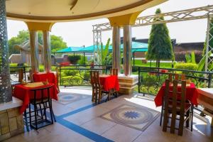 un restaurante con mesas rojas y sillas en un patio en Jade Spa and Hotel, en Kasese