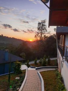 um pôr-do-sol a partir da varanda de uma casa com um passadiço de tijolos em POUSADA GRESSONEY MOUNTAIN em Monte Verde