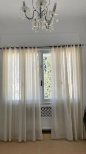 una ventana con cortinas blancas y una lámpara de araña en Nomads Hostel Tunisia en Túnez