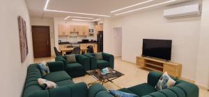 uma sala de estar com sofás verdes e uma televisão de ecrã plano em New amazing flat front of citystars mall no Cairo