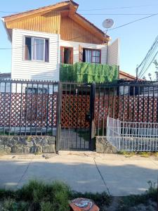 una cerca frente a una casa con muchos troncos en Habitaciones Pabla en Santiago