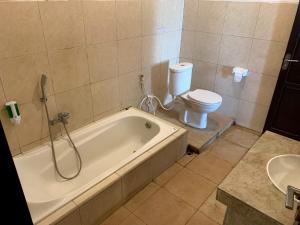 een badkamer met een bad en een toilet bij Tropical House Beach Bungalow in Kesembu