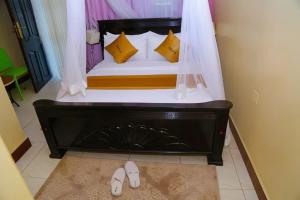 a bedroom with a bed with yellow pillows and shoes at Jade Spa and Hotel in Kasese