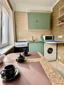a kitchen with green cabinets and a table with pots and pans at Apartment Budivelnykiv 22/11 in Kyiv