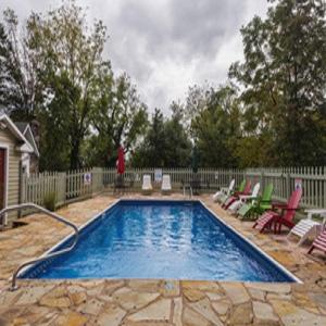 a swimming pool with chairs and a person standing next to it at The Mimslyn Inn in Luray