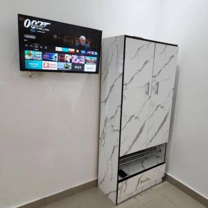 Elle comprend une armoire en marbre blanc et une télévision murale. dans l'établissement Asfranz Studio Apartment, à Abuja