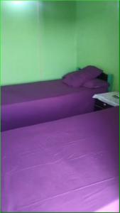 two beds with purple sheets in a room at Taam Al beeyout in Naj‘ al Maḩaţţah