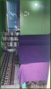 a room with a purple wall and stairs with a table at Taam Al beeyout in Naj‘ al Maḩaţţah