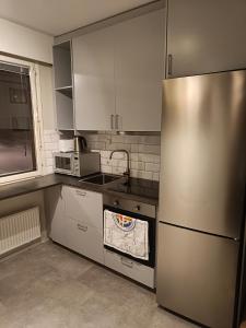cocina con nevera de acero inoxidable y microondas en Lägenhet på markplan, en Mariehamn