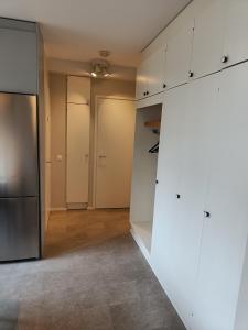 an empty kitchen with white cabinets and a refrigerator at Lägenhet på markplan in Mariehamn