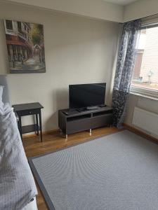 uma sala de estar com uma televisão de ecrã plano e uma mesa em Lägenhet på markplan em Mariehamn