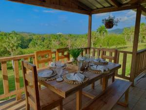 - une table en bois avec des assiettes et des verres sur une terrasse couverte dans l'établissement Vista al Valle, à San Felipe de Puerto Plata