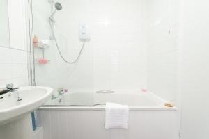 a white bathroom with a tub and a sink at Bosuns Chair in Lymington