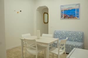 ein Esszimmer mit einem Tisch und weißen Stühlen in der Unterkunft Casa di Nonna Rosy in Neapel