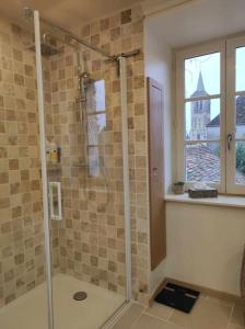 een badkamer met een douche en een glazen deur bij La maison du Boulanger in Pontaubert