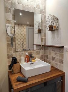 een badkamer met een witte wastafel en een spiegel bij La maison du Boulanger in Pontaubert