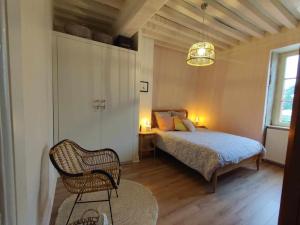 een slaapkamer met een bed en een stoel erin bij La maison du Boulanger in Pontaubert