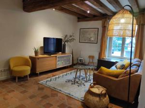 een woonkamer met een bank en een tv bij La maison du Boulanger in Pontaubert