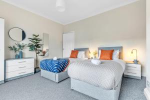a white bedroom with two beds and a chair at Inspira Stays - Modern Stylish 2 Bedroom House - Free Parking - Wi-Fi - Monthly Discount in Leicester