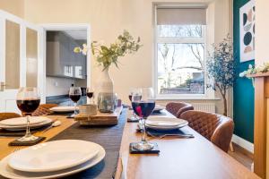 a dining room table with wine glasses on it at Inspira Stays - Monthly DISCOUNTS - Stylish Modern 2 Bedroom House - Free Parking - Wi-Fi in Leicester