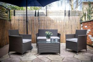 a patio with three chairs and a table and an umbrella at Inspira Stays - Modern Stylish 2 Bedroom House - Free Parking - Wi-Fi - Monthly Discount in Leicester