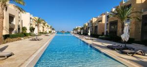 uma piscina com espreguiçadeiras e palmeiras num resort em Mangroovy El Gouna Full SEA View 1 BR, El Gouna em Hurghada