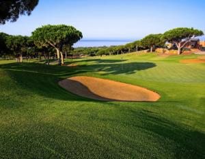 a green golf course with a large bunkerigunigunigunigunigunigunigunigun at Home Relax Calypso in Sitio de Calahonda