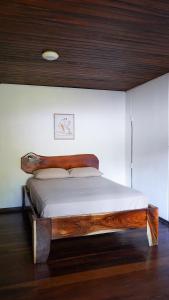 1 dormitorio con cama de madera y cabecero de madera en El Clan Hostel, en Puerto Viejo