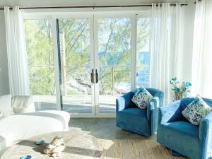salon z 2 niebieskimi krzesłami i dużym oknem w obiekcie Ocean Shire home w mieście Alice Town
