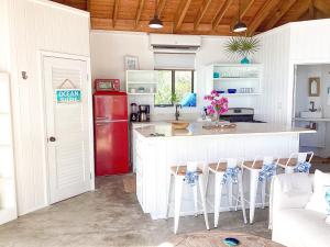 cocina con nevera roja y armarios blancos en Ocean Shire home, en Alice Town
