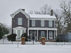 una casa con una cerca negra en la nieve en The Wynne House Inn, en Holly Springs