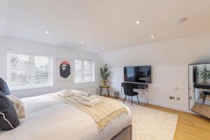 a white bedroom with a large bed and a television at Luxury 5 Bedroom House By The Sea in Brighton & Hove