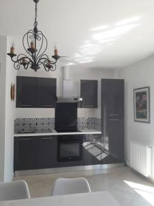 a kitchen with black cabinets and a chandelier at Maison dans une propriété avec une cour in Corneilhan