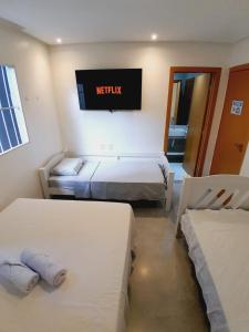 een kamer met 2 bedden en een tv aan de muur bij Casa Barramar Temporada 1 in Barra de São Miguel