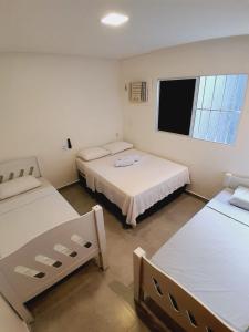 een kamer met 2 bedden en een flatscreen-tv bij Casa Barramar Temporada 1 in Barra de São Miguel