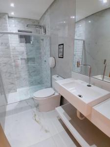 een badkamer met een toilet, een douche en een wastafel bij Casa Barramar Temporada 1 in Barra de São Miguel