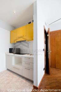 a kitchen with white counters and yellow cabinets at Suites Marilia Apartments - Suite Livorno Holiday Home Group in Livorno