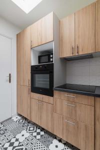 uma cozinha com armários de madeira e um forno preto em 4 pièces 90m2 centre Kremlin-Bicêtre - 6p em Le Kremlin-Bicêtre